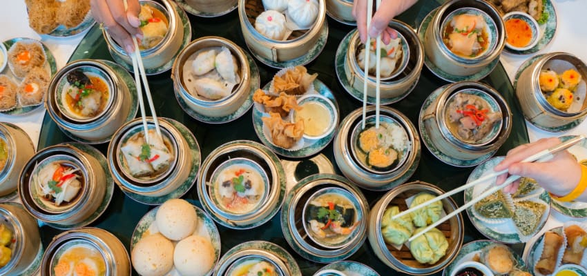 overhead view of a restaurant table full of dim sum plates