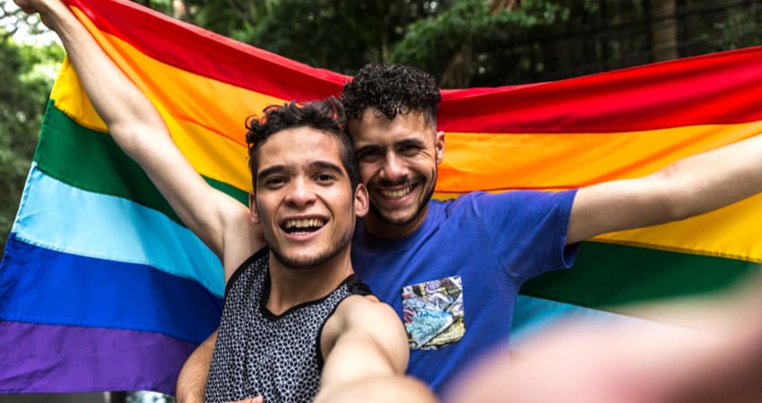 a gay couple holding a pride flag and smiling