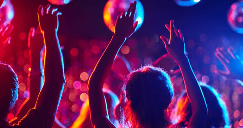 People partying in a dance club under disco balls.