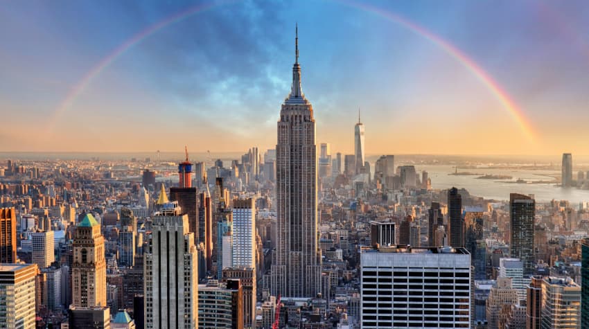 The Empire State Building from a distance, the surrounding city and a rainbow visible in the background
