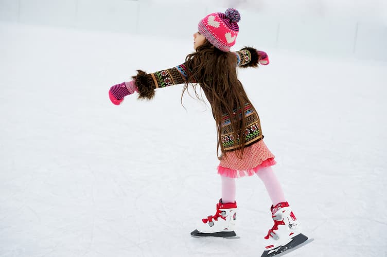 Little girl ice skating in winter clothes