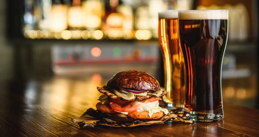 A beer and sandwich on the counter at a bar