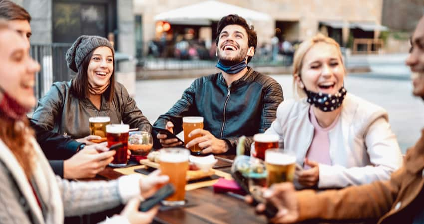 A group of friends having beer at a table outside with masks