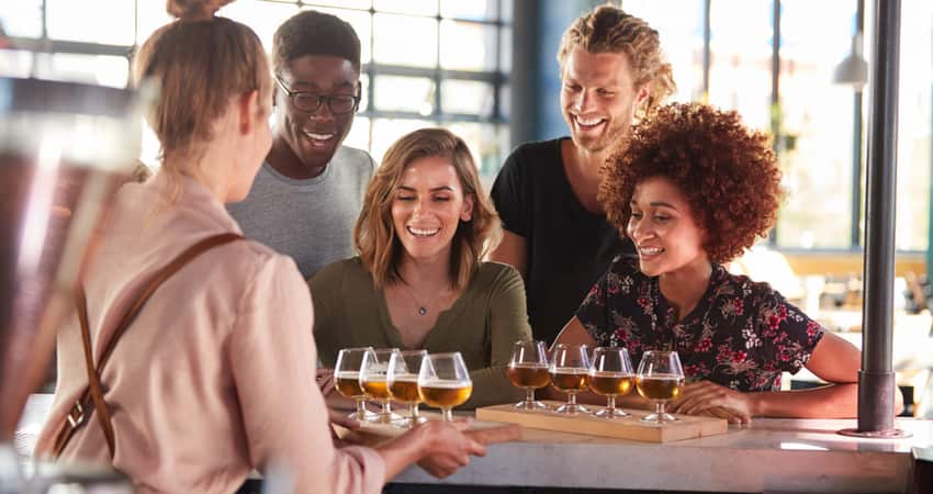 A group of friends at a brewery being served flights