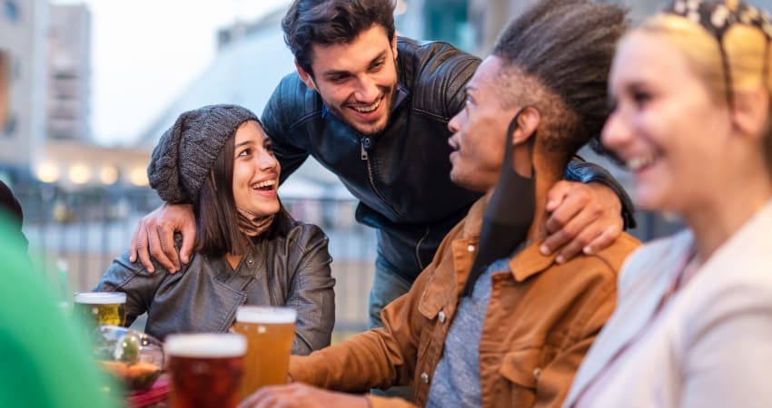 A group of friends with masks enjoying beers in an outdoor venue