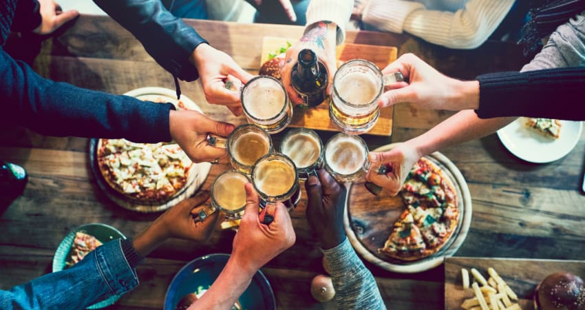 A large group of friends toast their glasses of beers