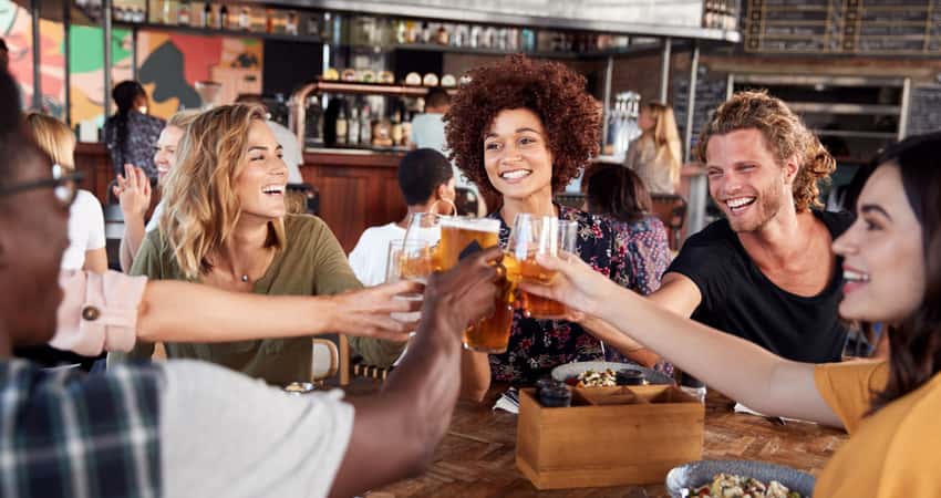 A group of friends toasting beer at a bar table