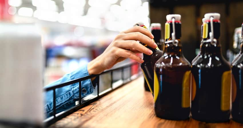 Close up of a hand grabbing beer at a store