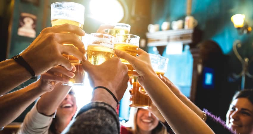 Close up a friends toasting beer at a pub