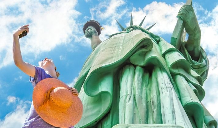 Woman taking selfie in front of the Statue of Liberty