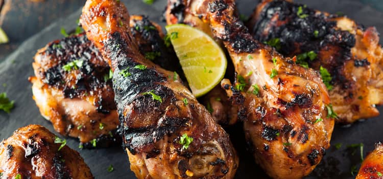 roasted chicken drumsticks arranged on a plate with a lemon slice