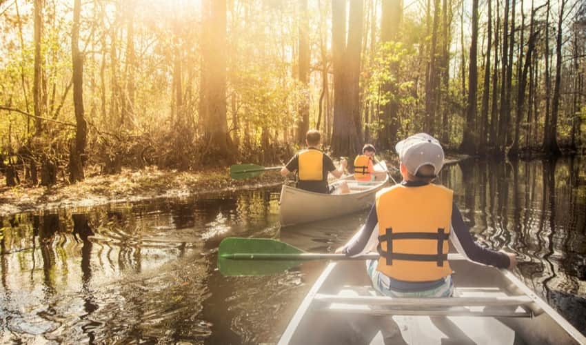 a group of people paddling in a canoe down a riverin a 