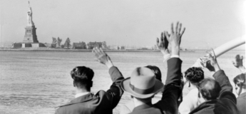 old photo of immigrants waving at the Statue of Liberty from a boat