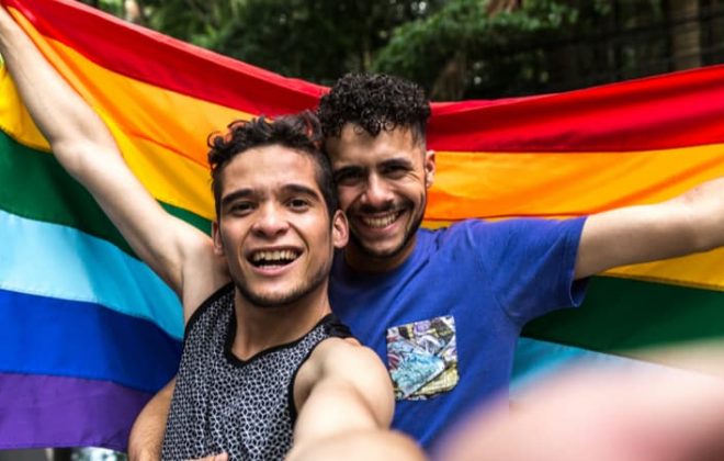 a gay couple holding a pride flag and smiling