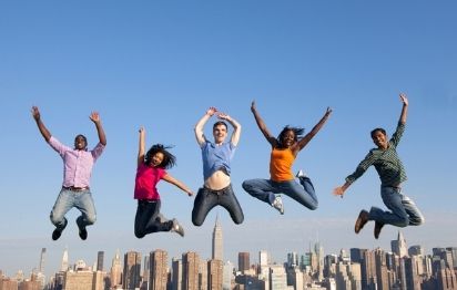 group of multi-racial people jumping in front of city skyline