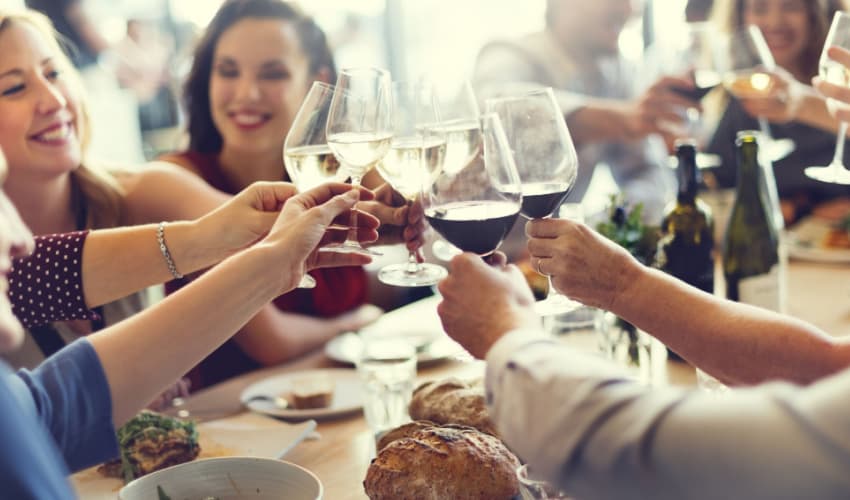 A group of people toasting wine over dinner