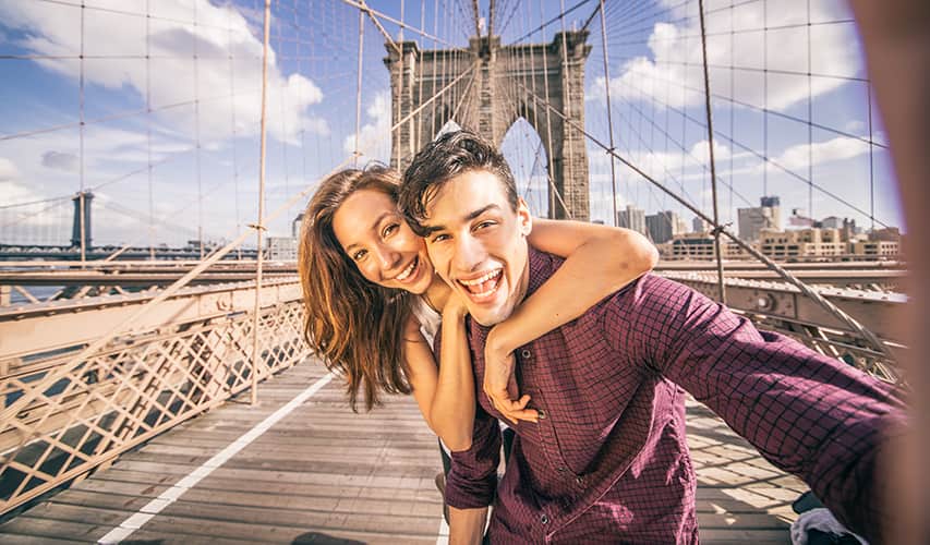 A happy couple take a selfie on the Brooklyn Bridge