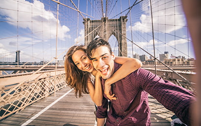 A happy couple take a selfie on the Brooklyn Bridge