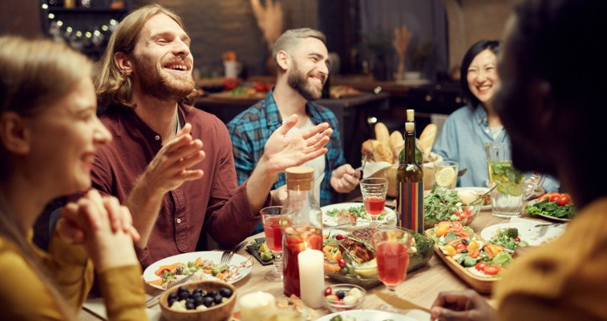 group of friends laughing and talking around a dinner table at a restaurant